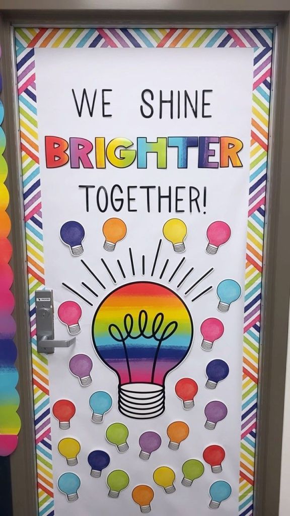 Bright and colorful classroom door with a rainbow light bulb and the phrase 'We Shine Brighter Together'.
