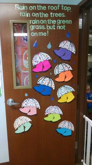 Spring classroom door with colorful umbrellas and rain boots – rainy day bulletin board idea for teachers.