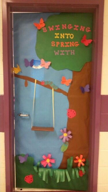 Whimsical spring classroom door with a swing hanging from a tree branch, surrounded by flowers and butterflies.