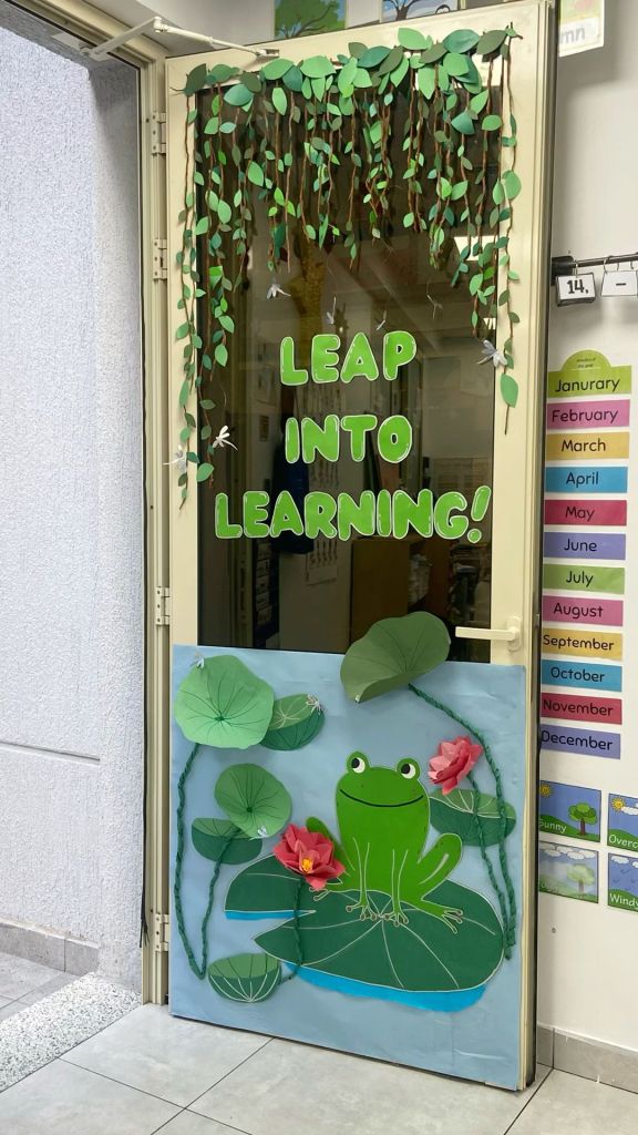 Pond-themed classroom door with a smiling frog on a lily pad and hanging vines, encouraging students to 'Leap Into Learning'.