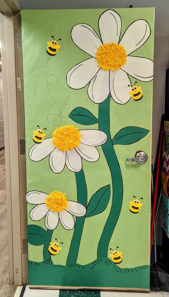Bee and daisy-themed spring classroom door featuring textured yellow flower centers and buzzing bees.