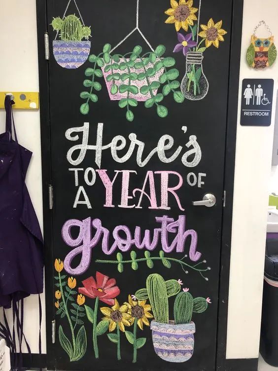 Chalkboard-style classroom door decorated with potted plants and vines, celebrating a year of growth.