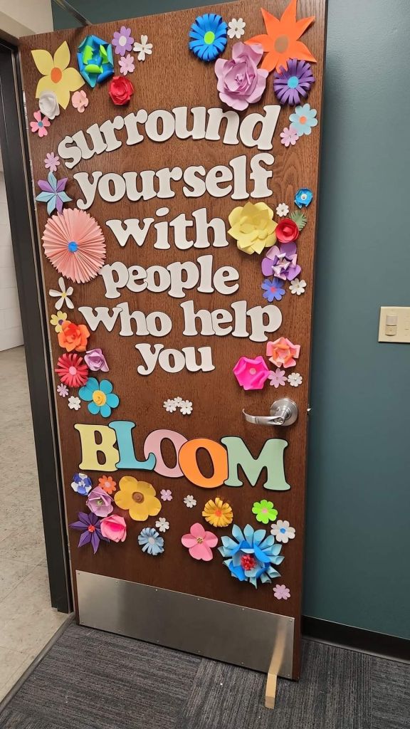 3D floral classroom door with the phrase 'Surround Yourself with People Who Help You Bloom'.