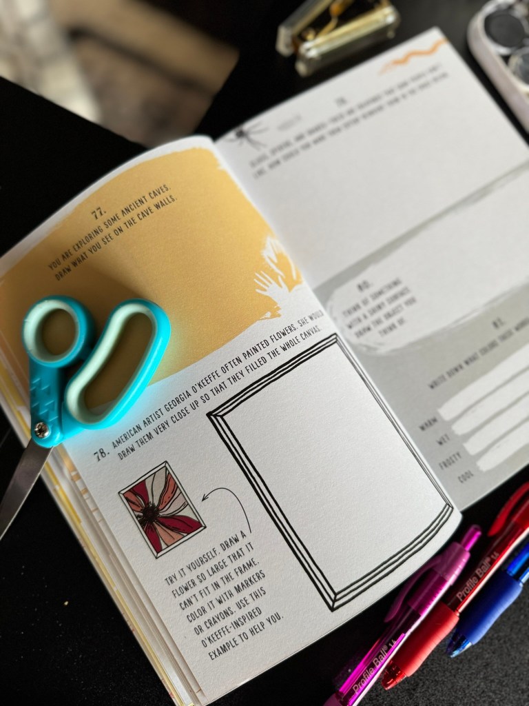 An open art prompt book page featuring colorful design elements, scissors, and markers, inviting creativity through guided drawing and exploration.