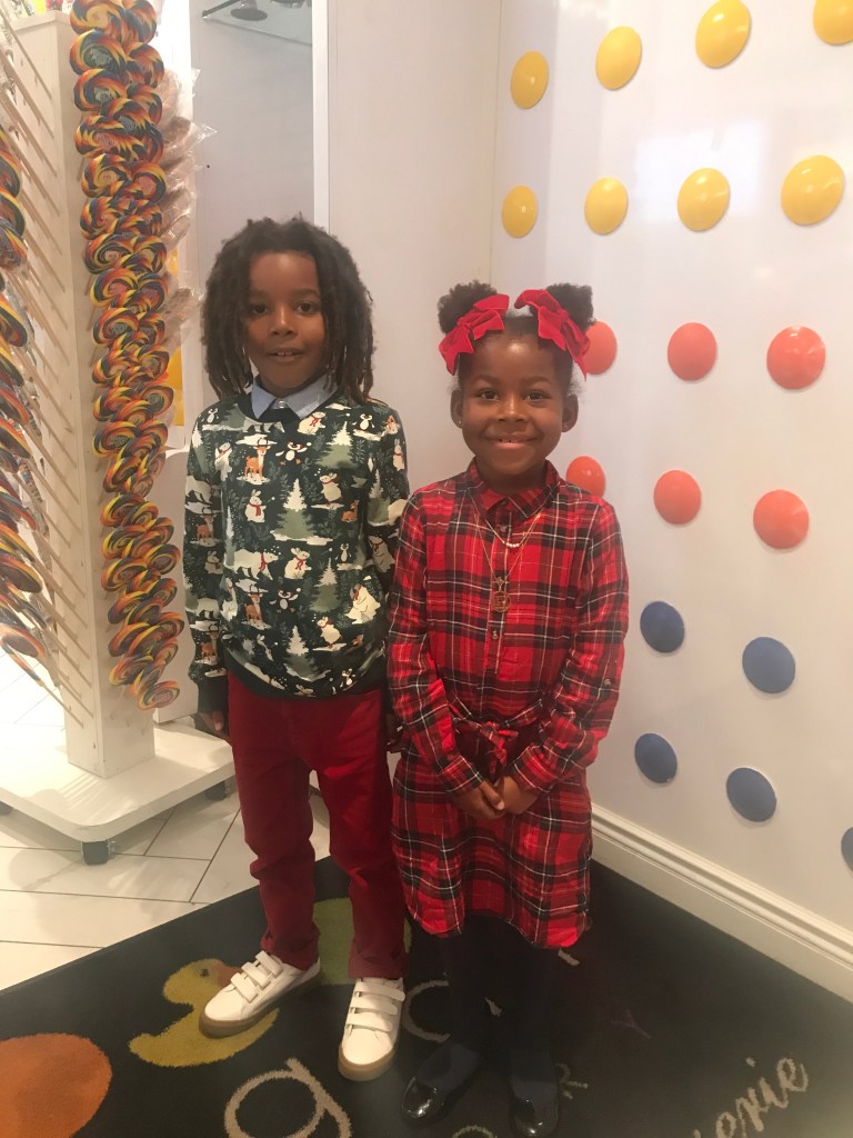 Two children posing in front of the Sugar Factory Biloxi sign during a family Christmas trip to Biloxi, Mississippi.
