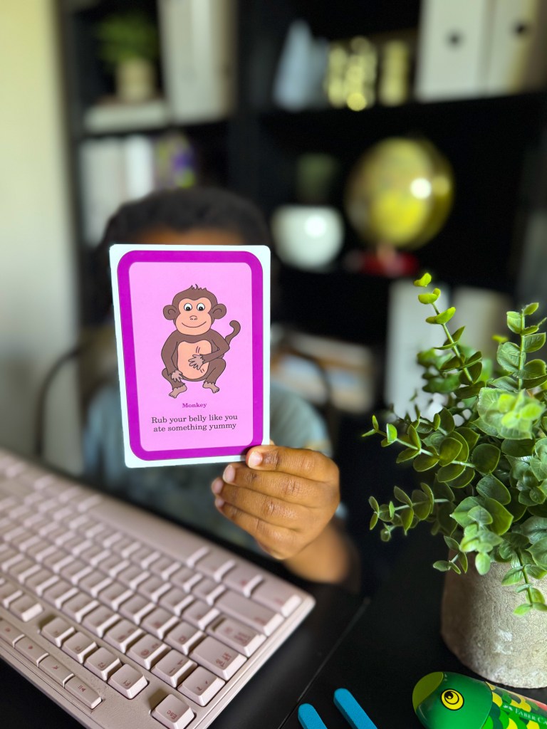 Child holding a monkey movement flashcard during an active kindergarten learning activity