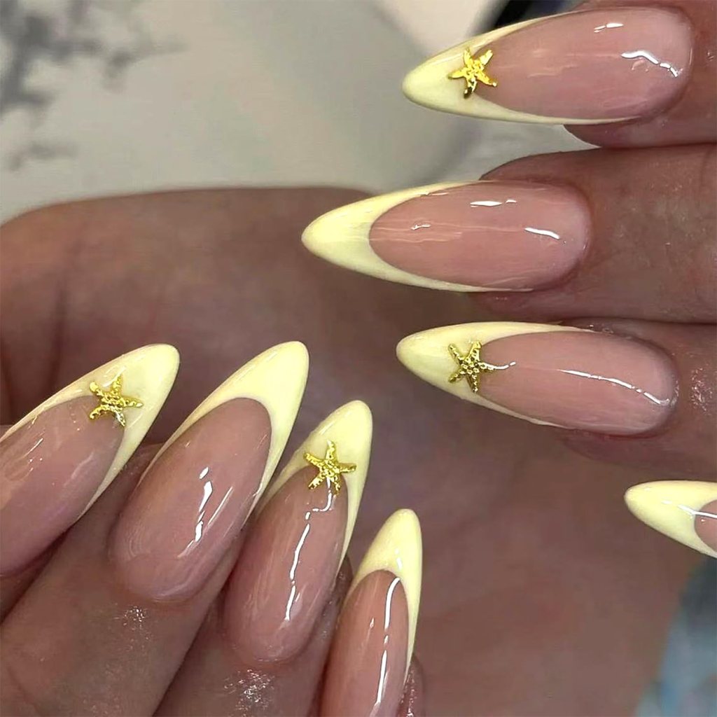Pastel butter yellow nails with gold star nail art and minimalist dotted accent nails