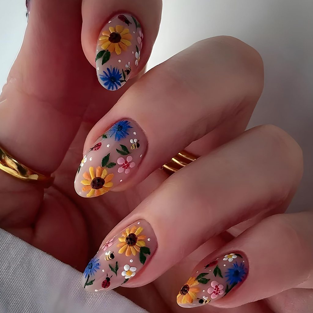 Close-up of manicured hands showing floral nail art with colorful flowers and leaves on a nude background.