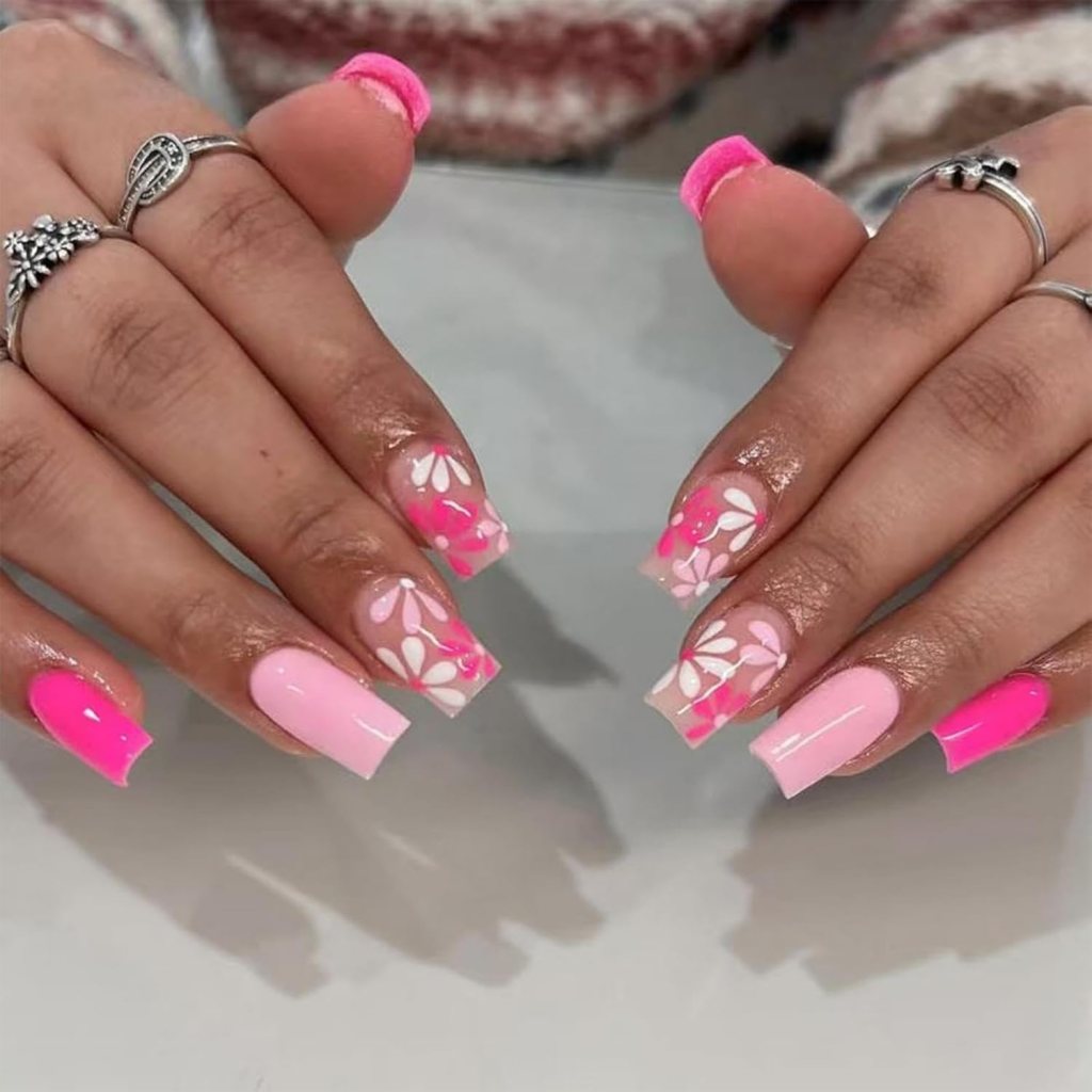 Close-up of well-manicured hands with pink and white nail art featuring floral designs.
