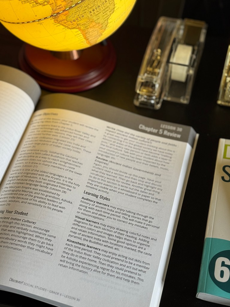 A close-up view of a glowing globe on a table beside an open social studies textbook, highlighting chapter content and learning styles.