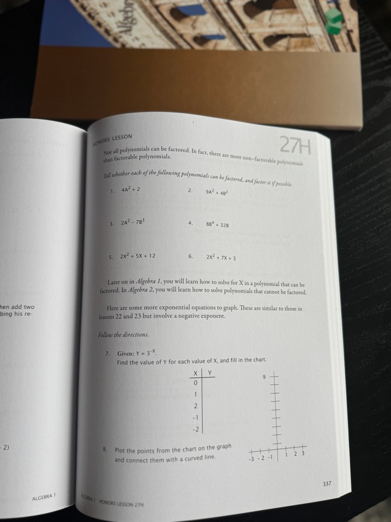 An open math workbook displaying an honors lesson on factoring polynomials and exponential equations, with sample problems and a graphing exercise.