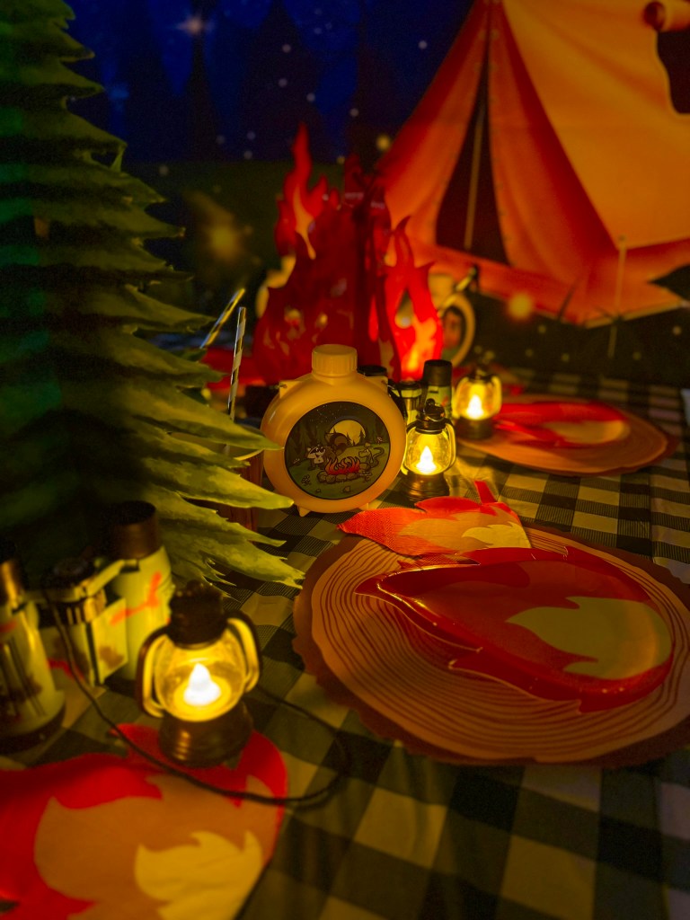 Cozy campfire birthday party table with glowing lanterns and outdoor adventure decorations.