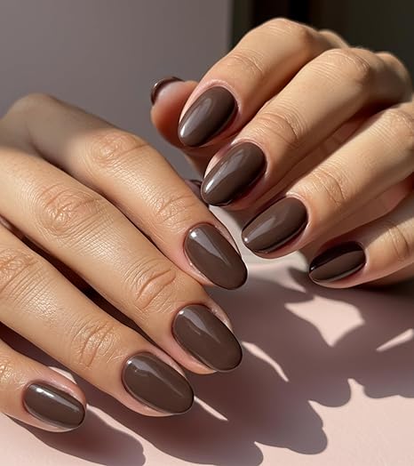 Close-up of hands with glossy deep chocolate brown almond-shaped nails, showcasing a sophisticated and elegant autumnal look.