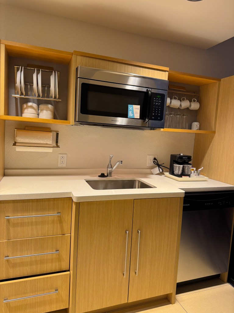 Hotel suite kitchenette with sink, microwave, dishwasher, dishes and coffee maker at Home2 Suites Pigeon Forge.