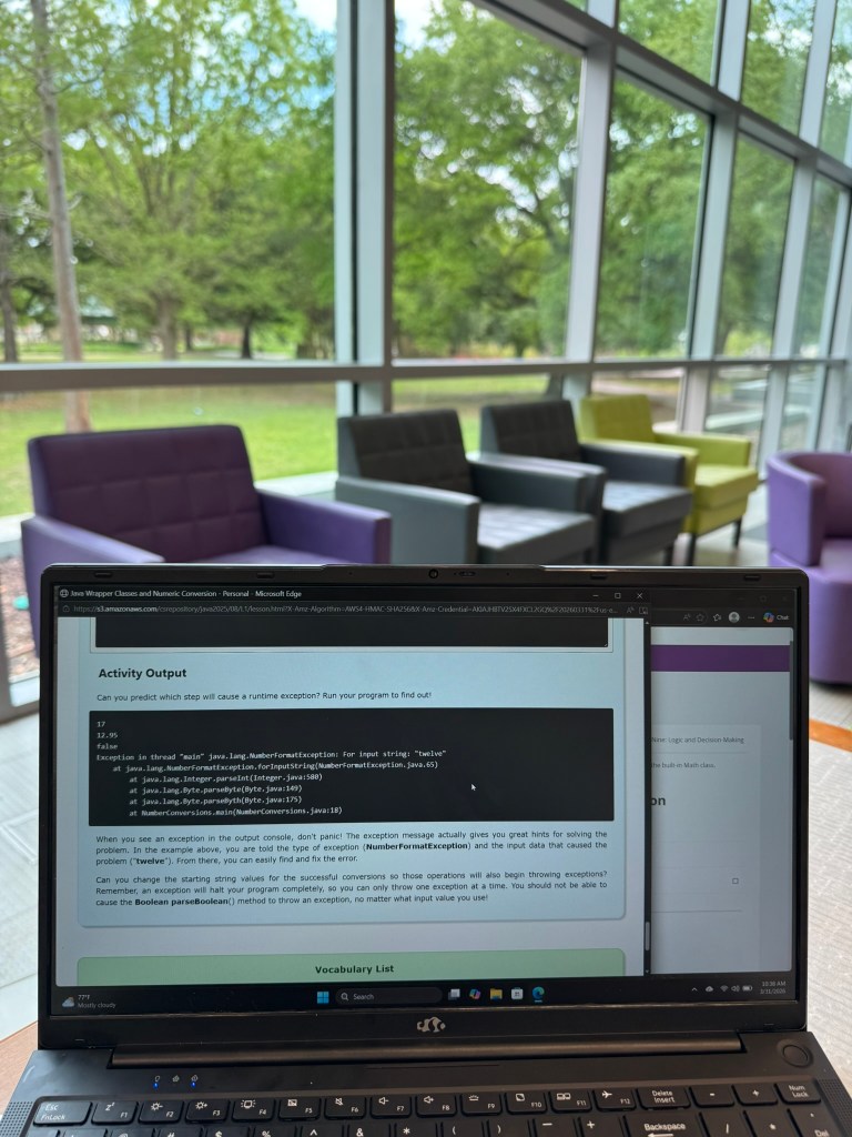 A laptop screen displaying a coding error message in a Java programming environment, with blurred colorful chairs and greenery visible through a large window in the background.