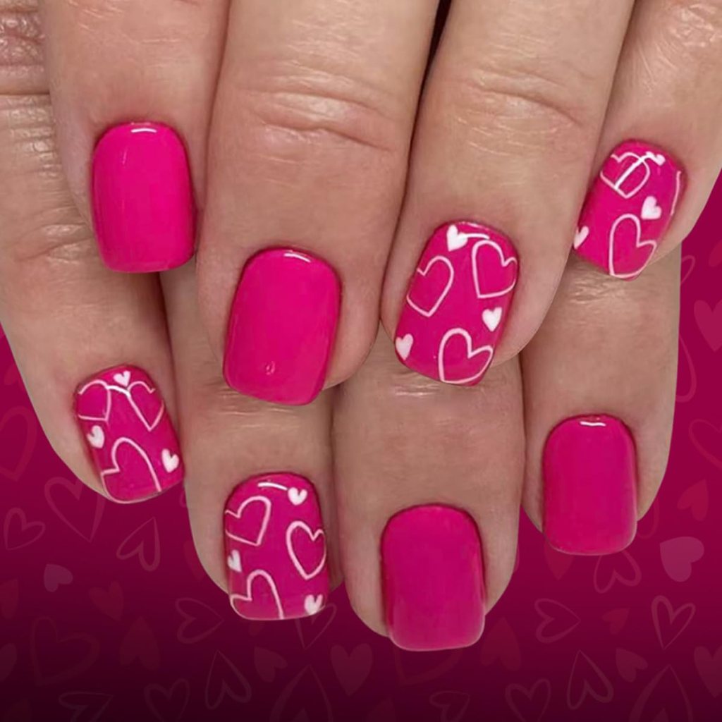 Close-up of manicured hands with bright pink nail polish and designs featuring white hearts on some nails.