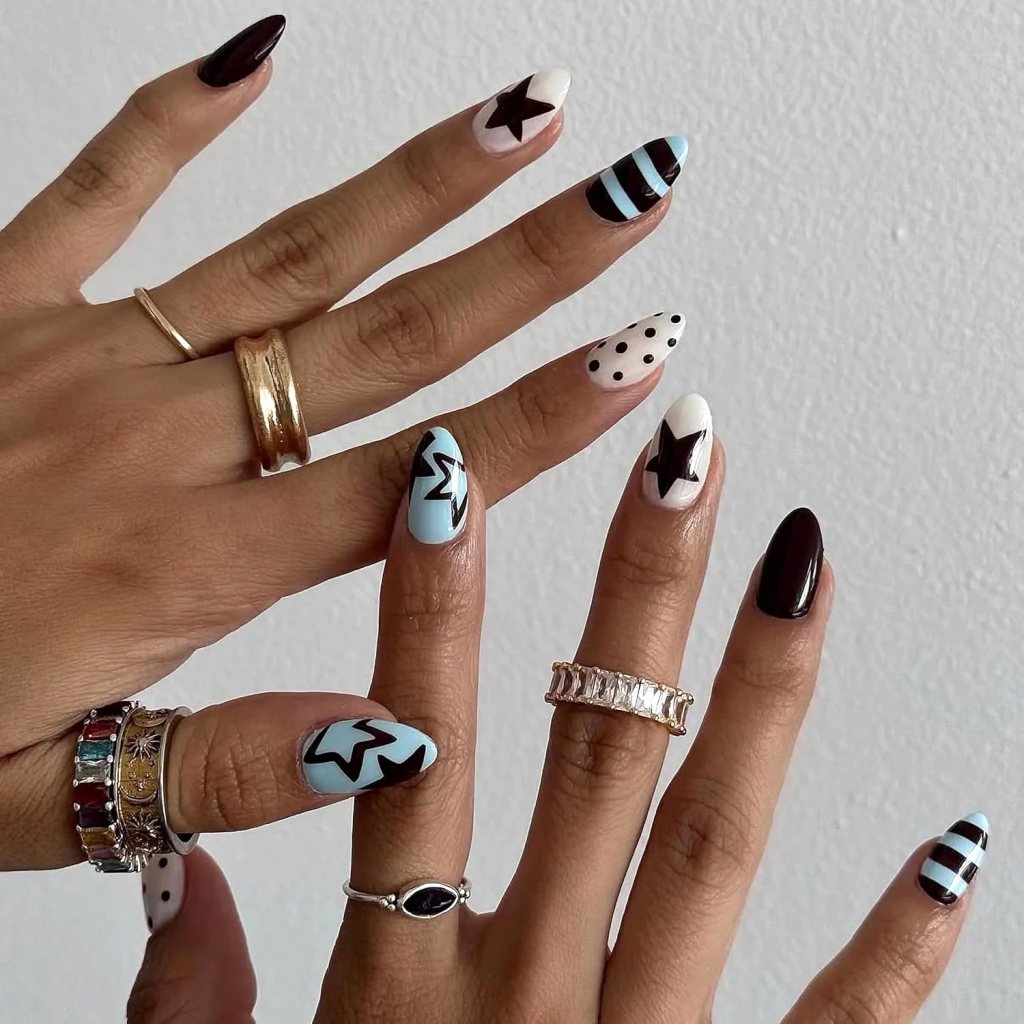Navy blue star and stripe almond nails with mix-match patterns including polka dots, stripes, and abstract star nail art.