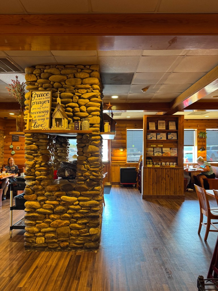 Stone fireplace with decorative farmhouse signs inside the cozy dining room at Flapjack's Pancake Cabin.