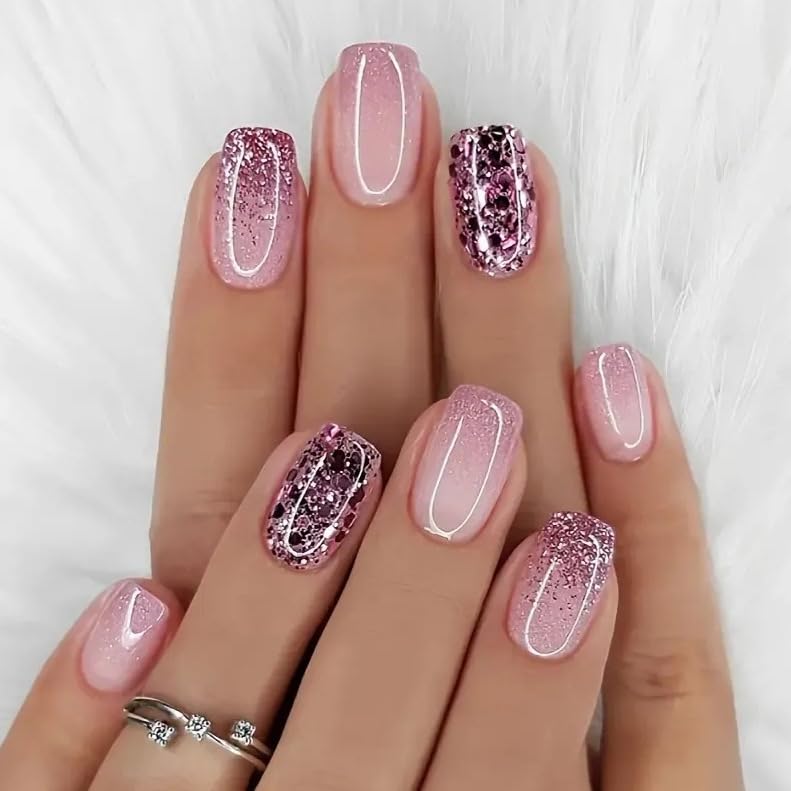 Close-up of manicured nails featuring a gradient pink design with glitter and a sparkling accent nail.
