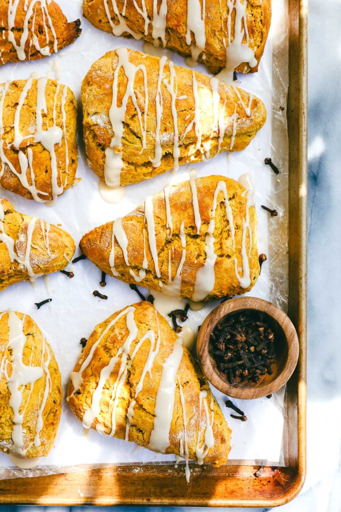 Freshly baked pumpkin scones drizzled with vanilla glaze – cozy fall breakfast idea