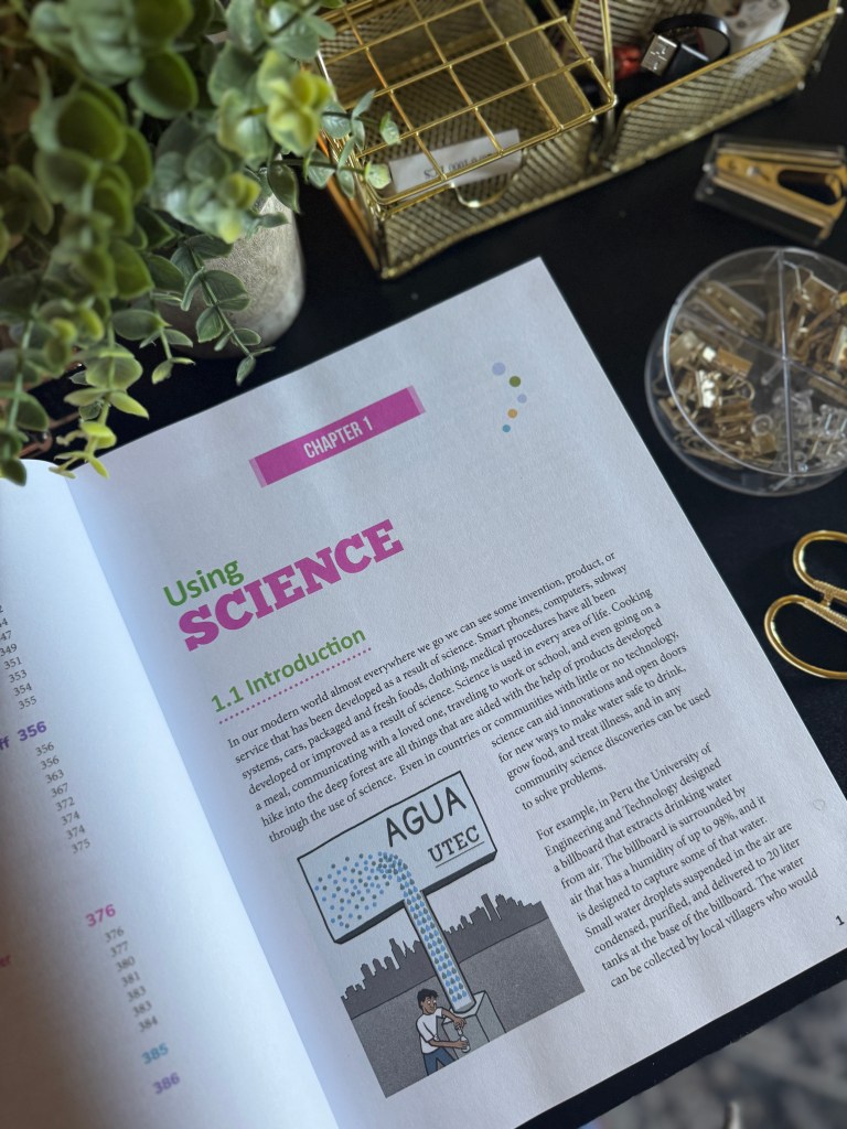 A page from the Real Science 4 Kids Book 7 textbook, featuring the title 'Using Science' and an illustration of a boy collecting water from a sign that reads 'AGUA UTEC'. The background includes plants and school supplies.