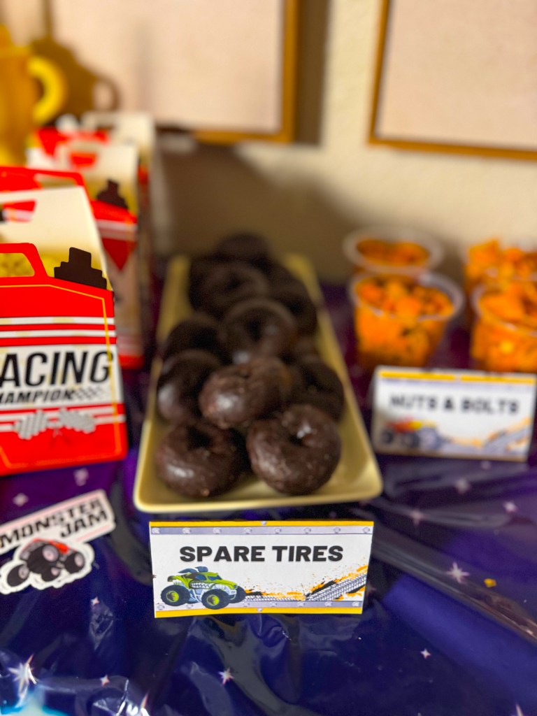 Monster truck birthday party snack idea called spare tires made with chocolate mini donuts on a racing themed snack table.