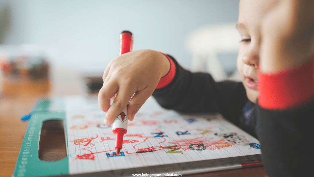 Young child practicing drawing and early writing skills with markers during homeschool preschool.
