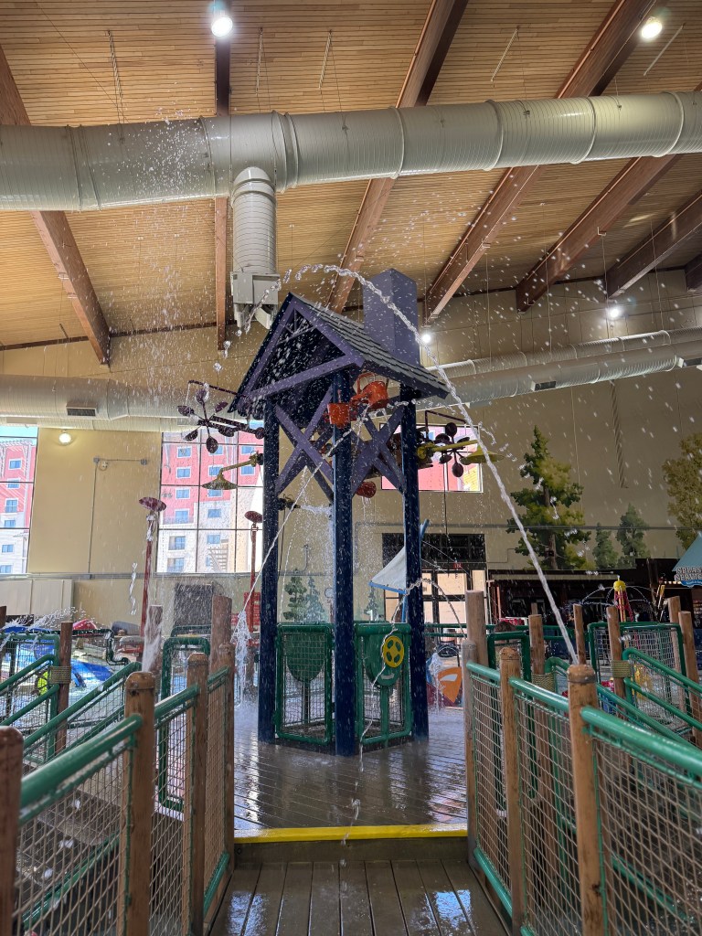 Indoor water play area at Great Wolf Lodge featuring a colorful water structure with water spraying from various points.