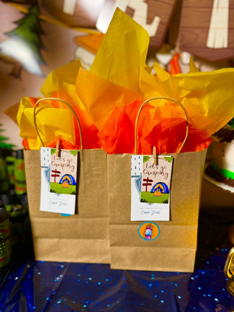 Close-up of camping birthday party favor bags with “Thanks for joining us at Camp June” tags.