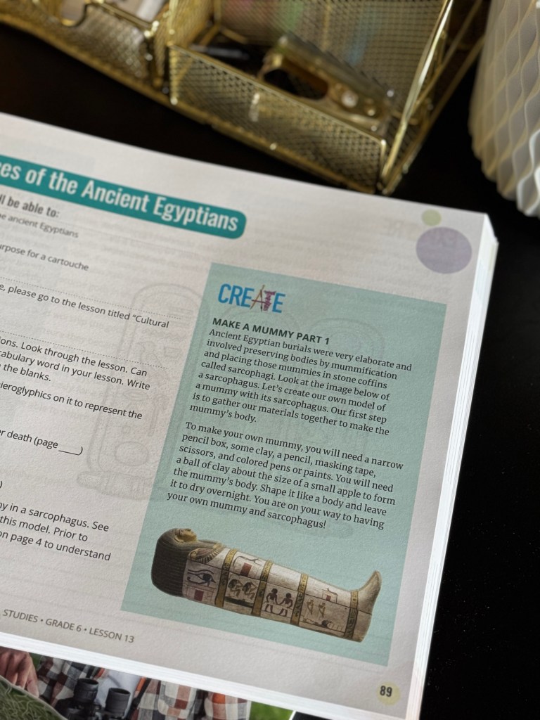 A close-up of a lesson page from a social studies curriculum, titled 'Make a Mummy Part 1,' featuring instructions and materials needed for a hands-on activity about Ancient Egyptian mummification.