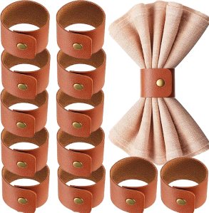 A set of cloth napkin rings made from brown leather, arranged neatly with one napkin folded and secured in the center.