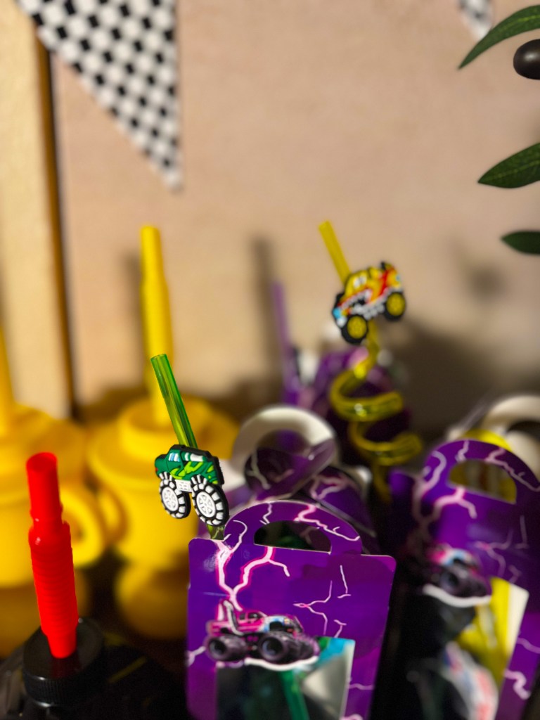 Monster Jam birthday party favors and drinks with monster truck themed straws and racing party decorations.