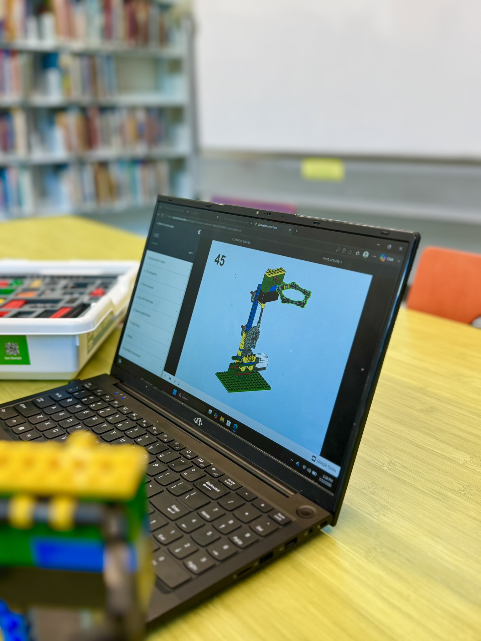 Laptop screen showing step 45 of a LEGO robotics instruction in an educational setting