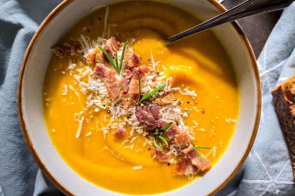 Velvety Italian pumpkin soup garnished with toasted pumpkin seeds and fresh basil