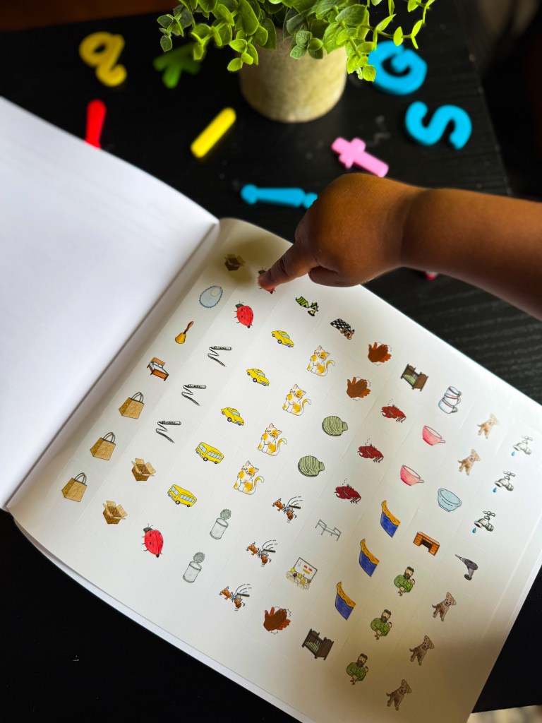 Child pointing to colorful picture stickers included in the Spelling You See Level A kindergarten spelling curriculum.