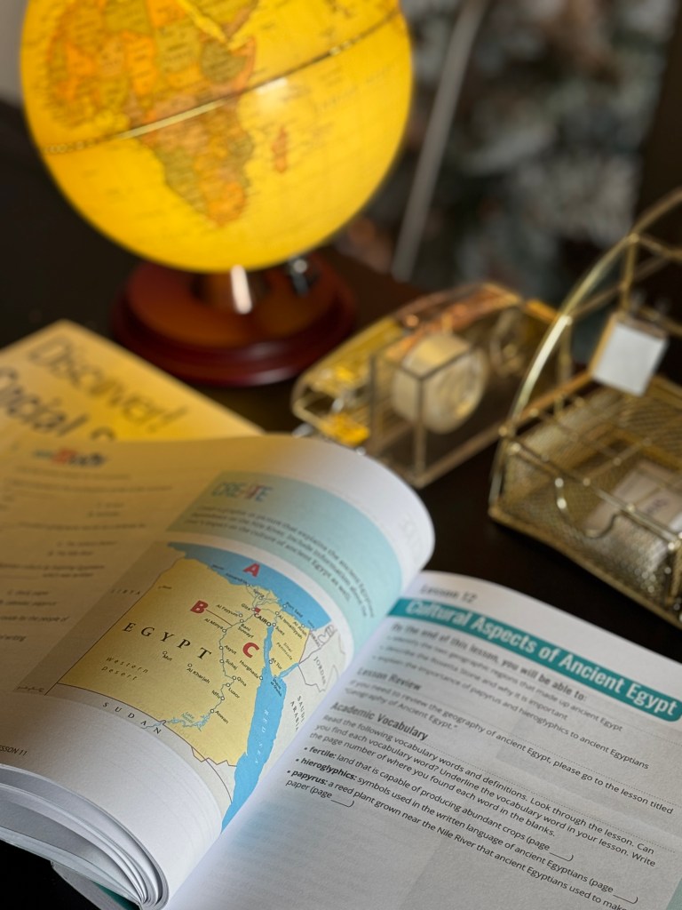 An open educational book featuring a map of Egypt beside a glowing globe, highlighting a social studies lesson on Ancient Egypt.