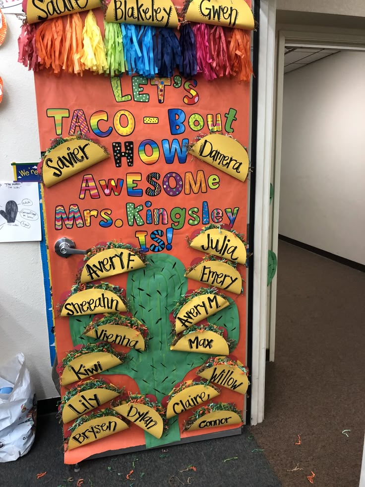 A decorated classroom door with a taco theme, featuring the phrase 'LET'S TACO - BOUT HOW AWESOME Mrs. Kingsley IS!' and colorful taco cutouts displaying student names, set against a vibrant orange background.