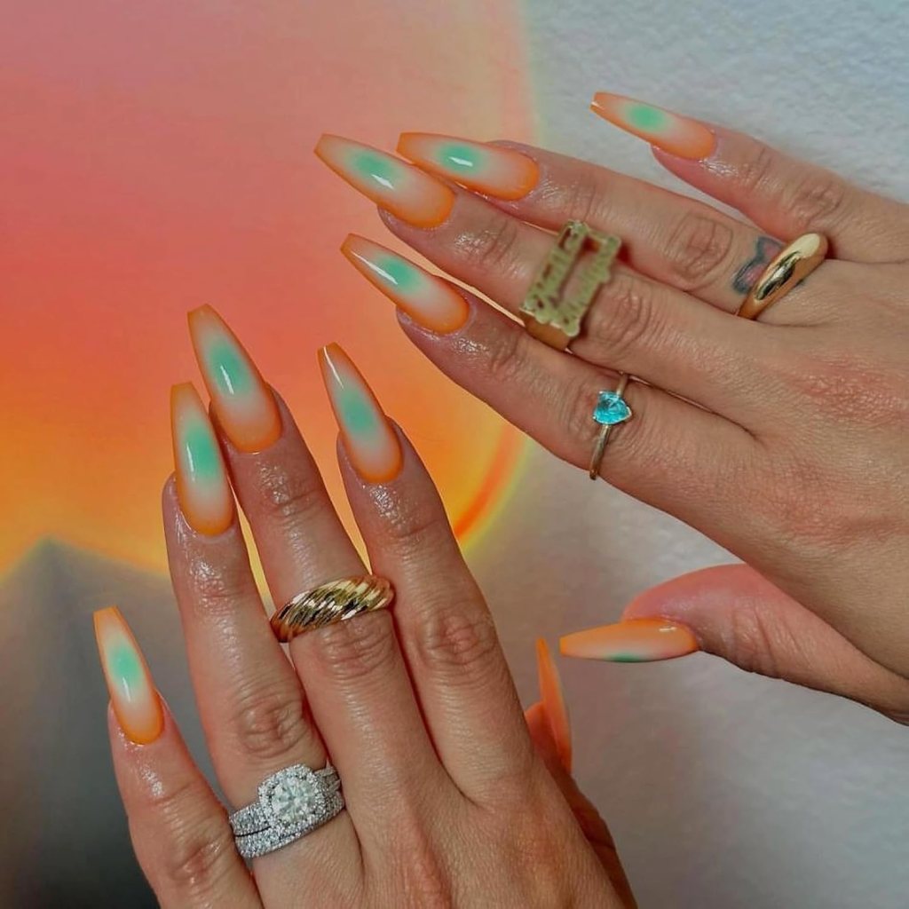 Almond nails with soft orange aura glow effect on a sheer base