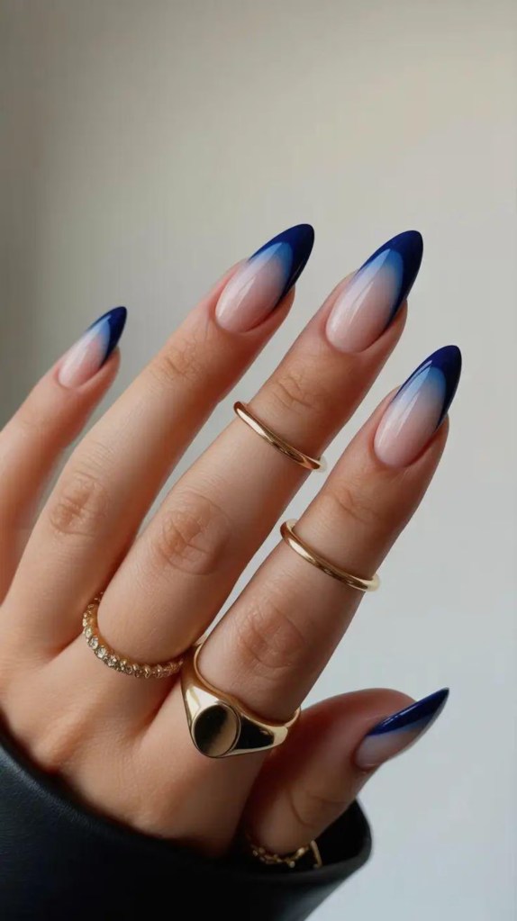 Ombre navy blue French tip almond nails with a soft gradient fade and glossy nude pink base.