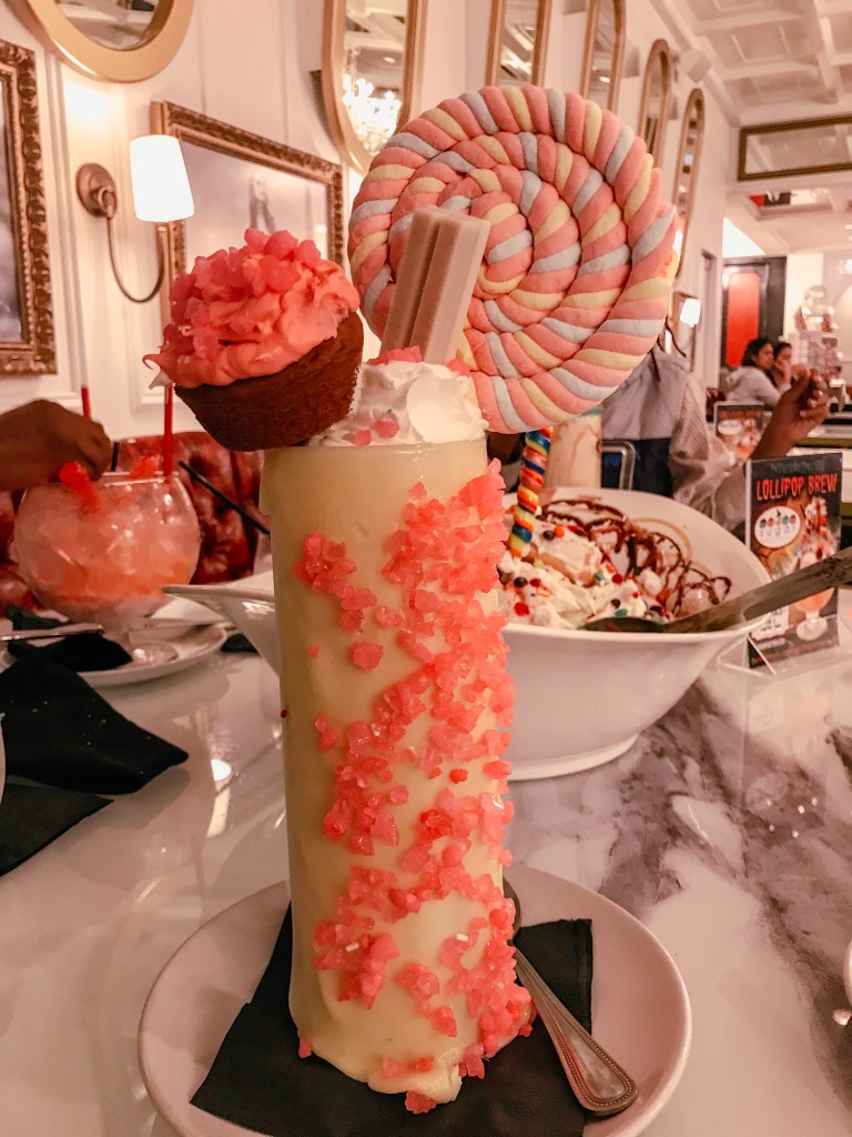 Colorful specialty milkshake topped with whipped cream and candy at Sugar Factory Biloxi.