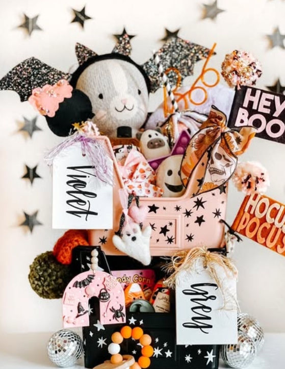 A pastel-themed boo basket featuring a plush bat-eared kitty, Halloween treats, and decorative tags. The basket is styled with playful items like candy, plush toys, and festive pennants, creating a whimsical and kid-friendly Halloween display.