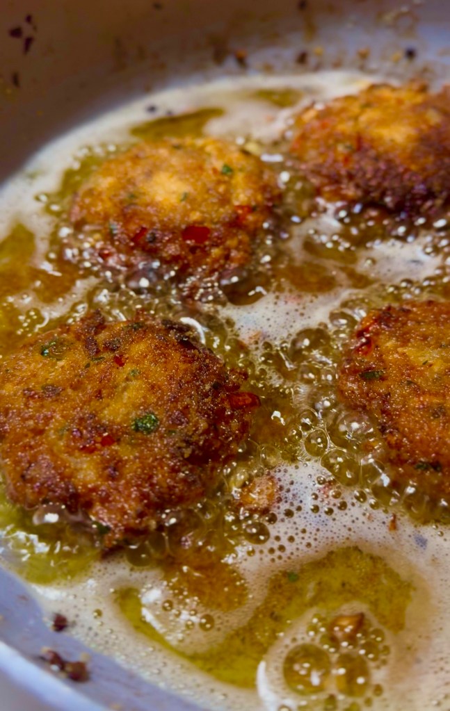 Golden brown fried salmon patties cooking in bubbling oil.