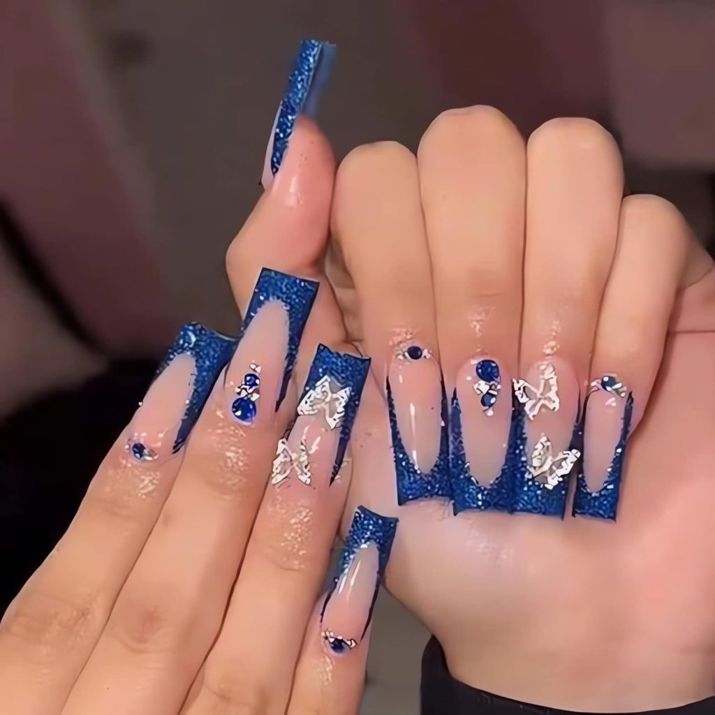 Navy blue glitter French tip coffin nails with rhinestones and silver chrome accents on nude acrylic nails.