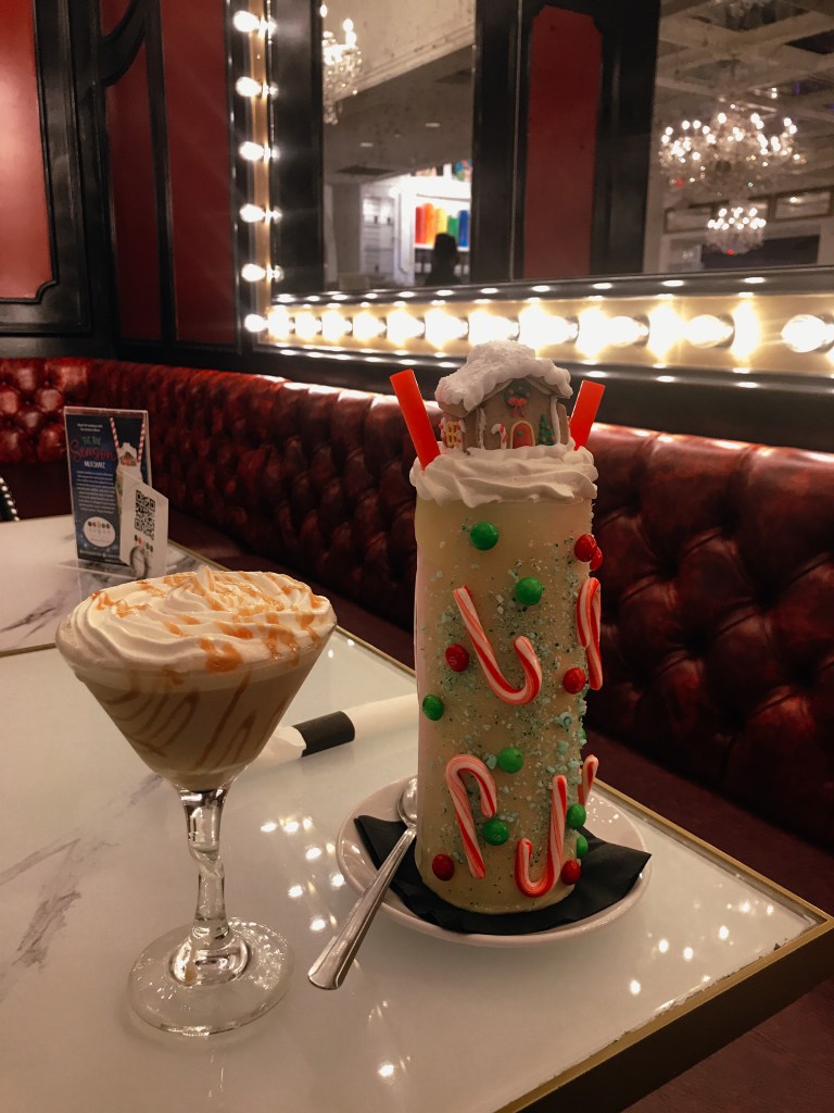 Sugar Factory Biloxi limited-edition Christmas milkshake topped with whipped cream, candy canes, colorful candy, and a miniature gingerbread house.