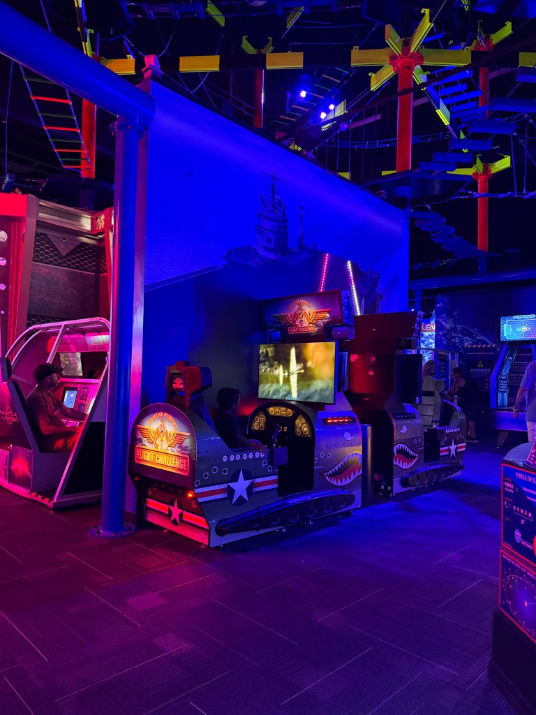 Arcade area featuring colorful flight simulation games with vibrant lighting and themed designs.