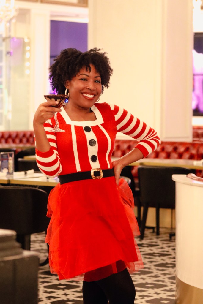 Woman in a festive Santa dress holding an espresso martini at Sugar Factory Biloxi during a Christmas getaway on the Mississippi Gulf Coast.