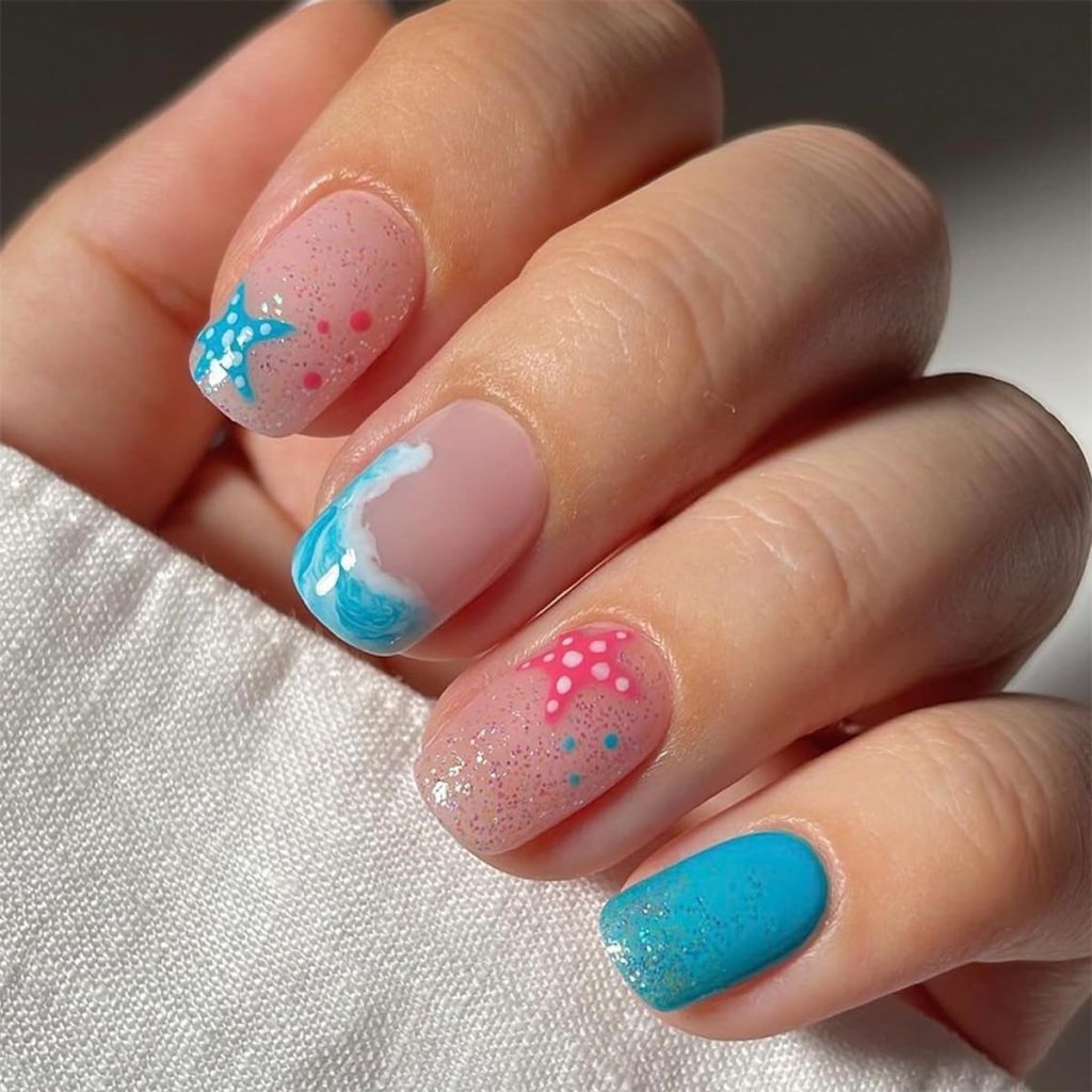 Cute ocean nails with pink starfish accents, blue wave nail art, and beach-inspired glitter details