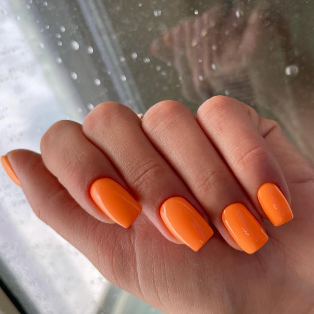 Glossy neon orange square nails in a bold solid color manicure
