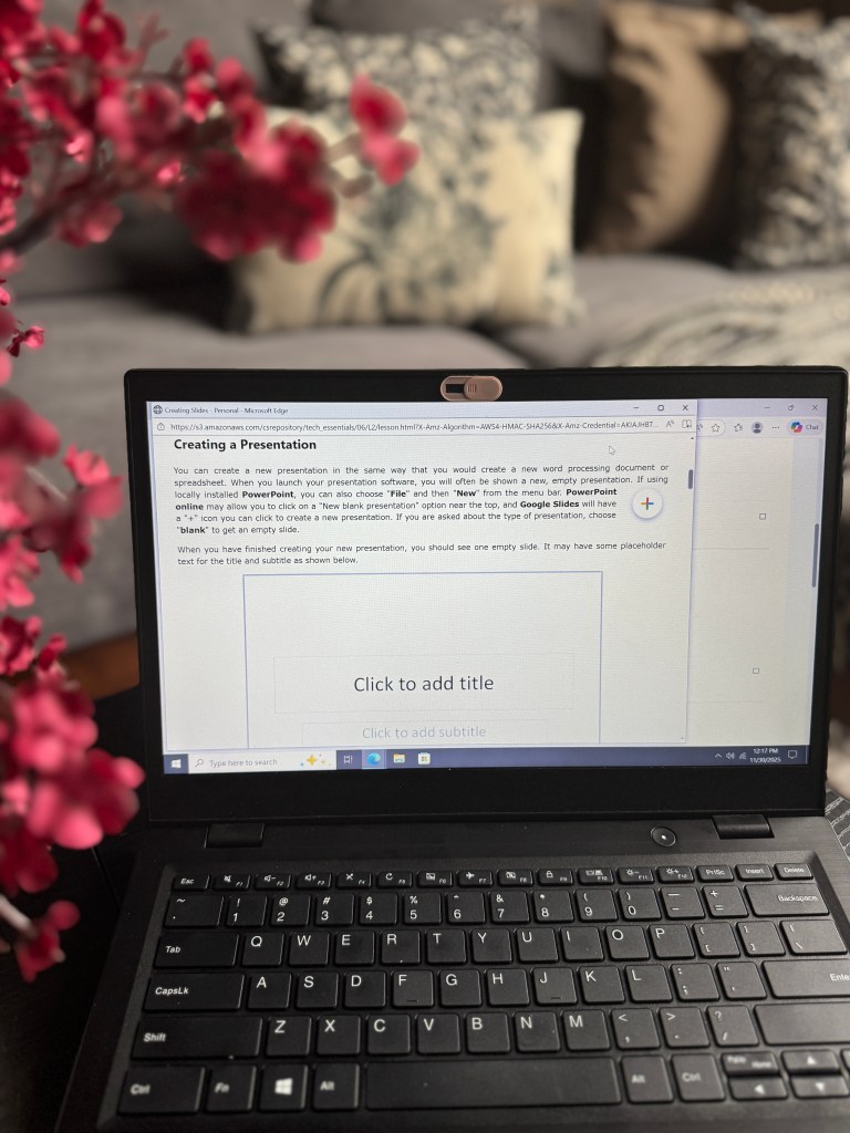 A laptop displaying a presentation creation interface with floral decor in the foreground.