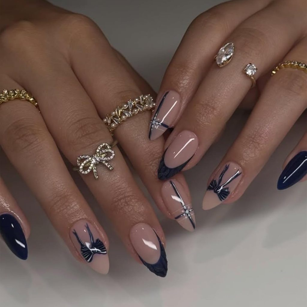 Navy blue bow almond nails with glossy nude polish, bow nail art, and dark blue French tip accents.